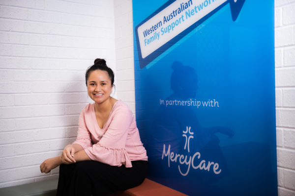 Kat sitting down at work in front of the branded wall