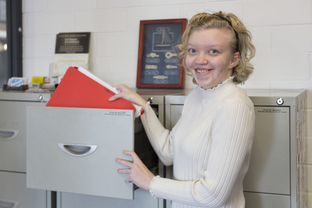 Tayla grabbing a file from a cabinet