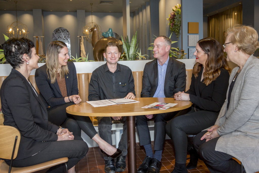 Group of people sitting around a table smiling and talking