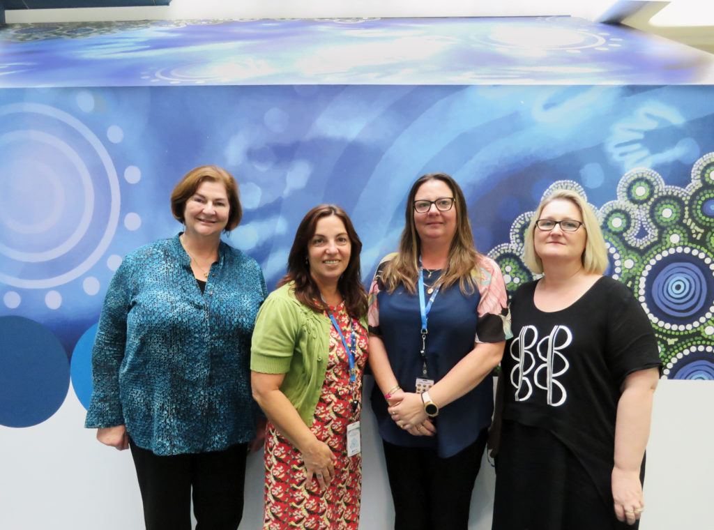 One Edge employee standing with three Water Corporation staff in front of a blue graphic