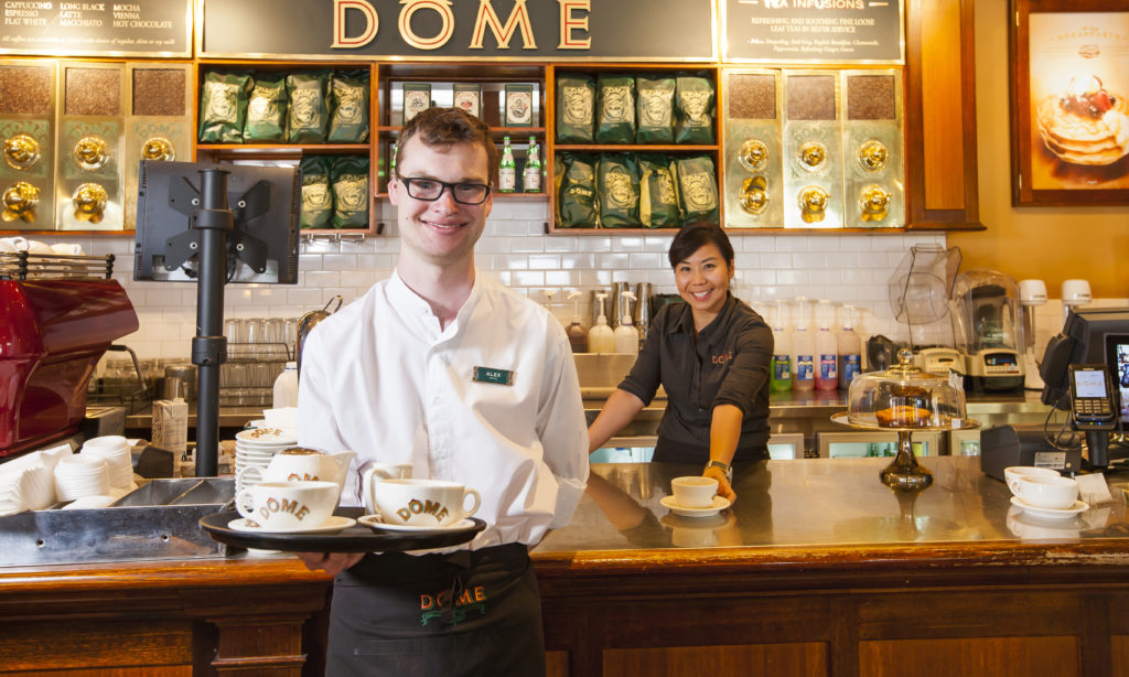 Alex standing in front of the counter at Dome with his colleague behind him.