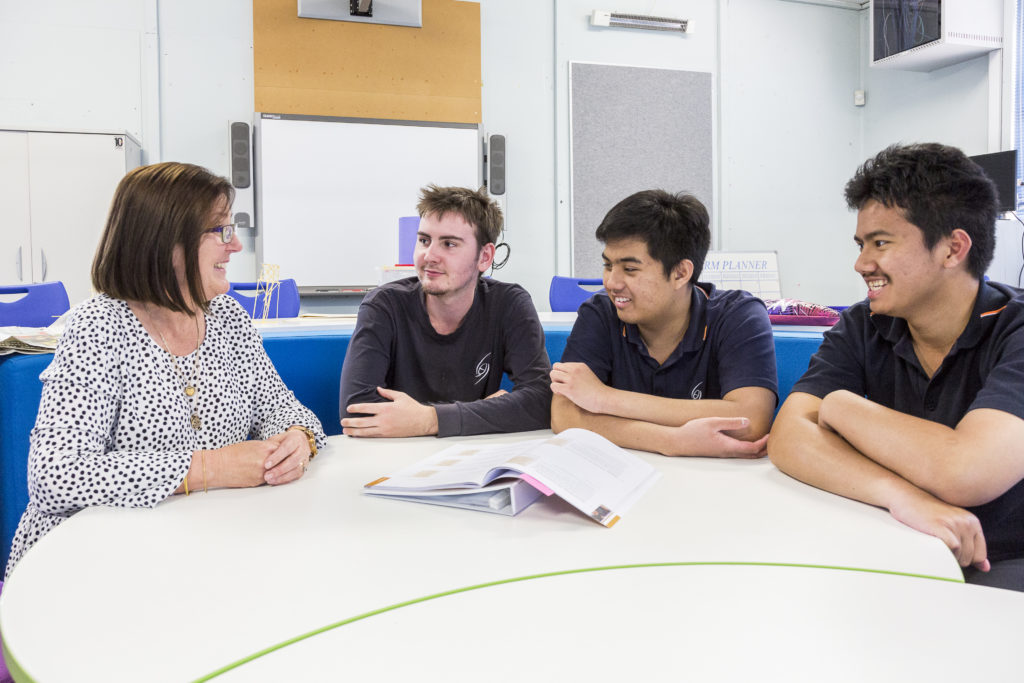 Woman walking to three male students