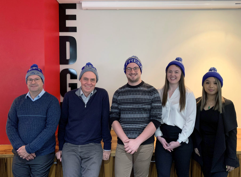 5 Edge staff members smiling with blue beanies on