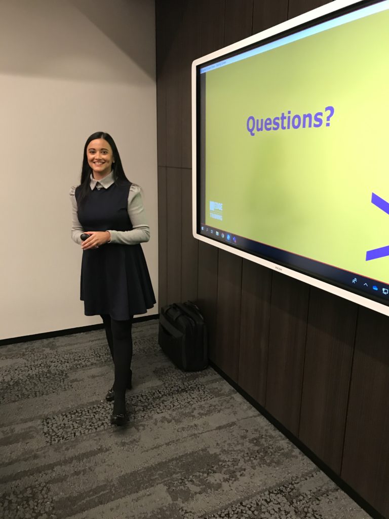 Woman smiling for the camera in front of a presentation slide