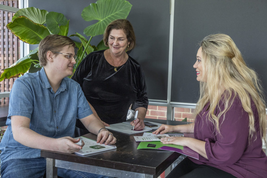 Three people sitting around a table smiling together