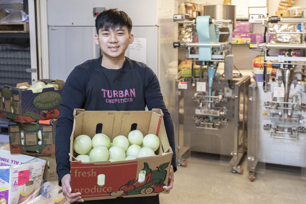 Darren smiling while holding a box of onions.