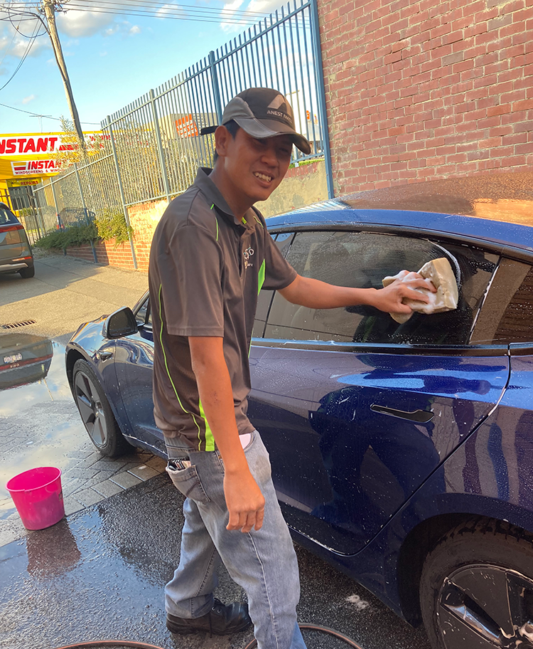 John smiling while cleaning a blue car.