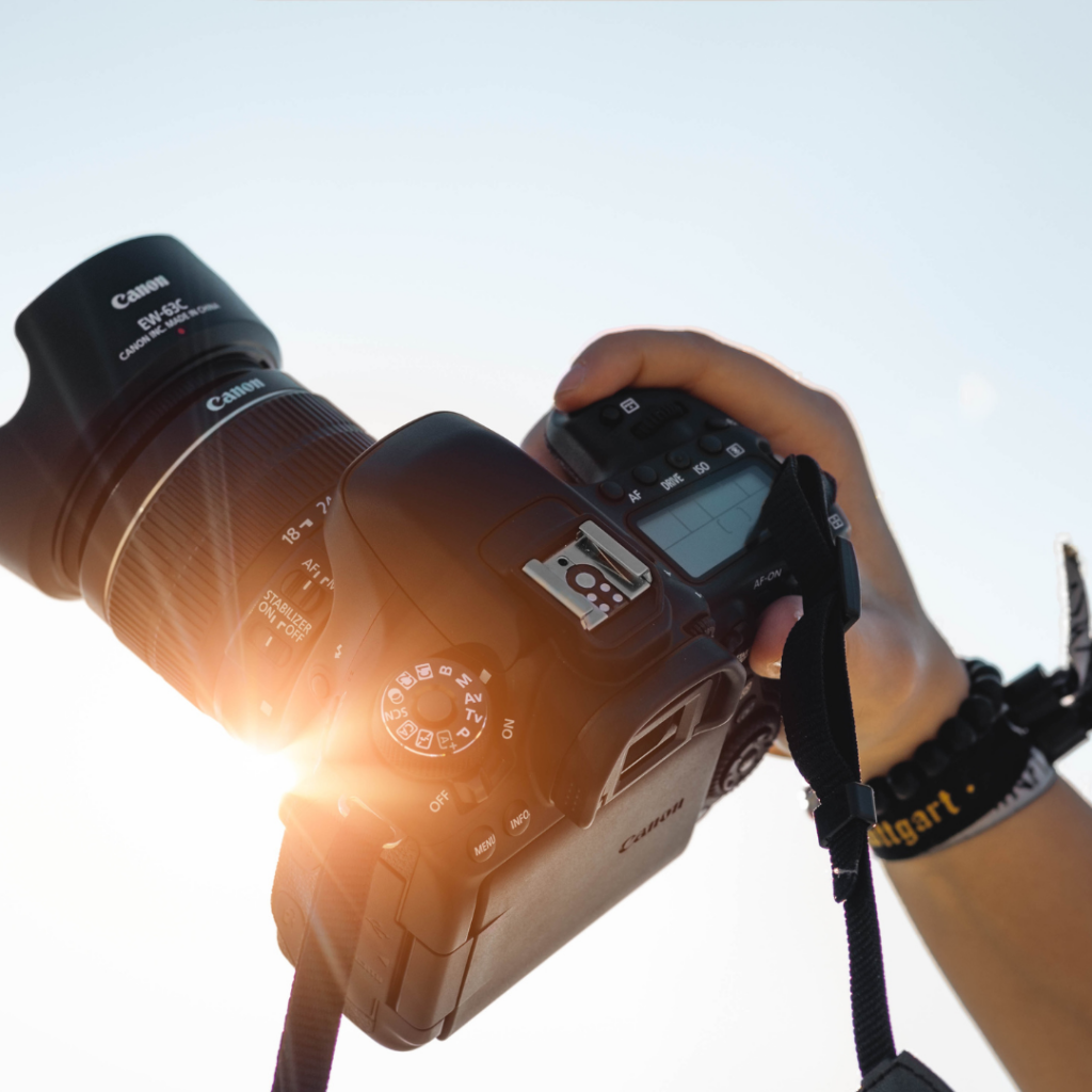 photo of a camera being held up to the sky with a sunflare