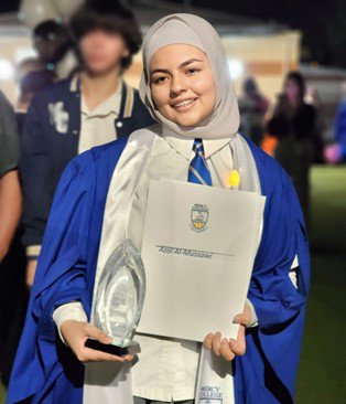 Azal at her high school graduation holding a certificate in one hand and a trophy in the other.