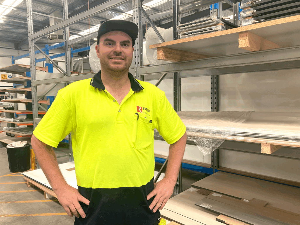 Kyle standing with his hands on his hips and smiling. He is wearing a hat and high-vis t-shirt.