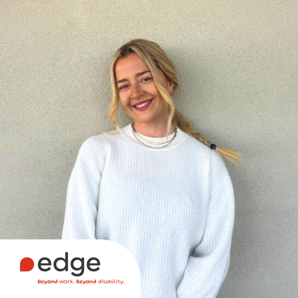Mid-shot image of Beth smiling. She is wearing a white knitted jumper. In the bottom left of the image is the Edge logo and slogan: Beyond work. Beyond disability.